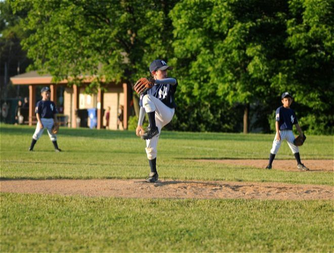 Three young kids outside playing baseball at a park